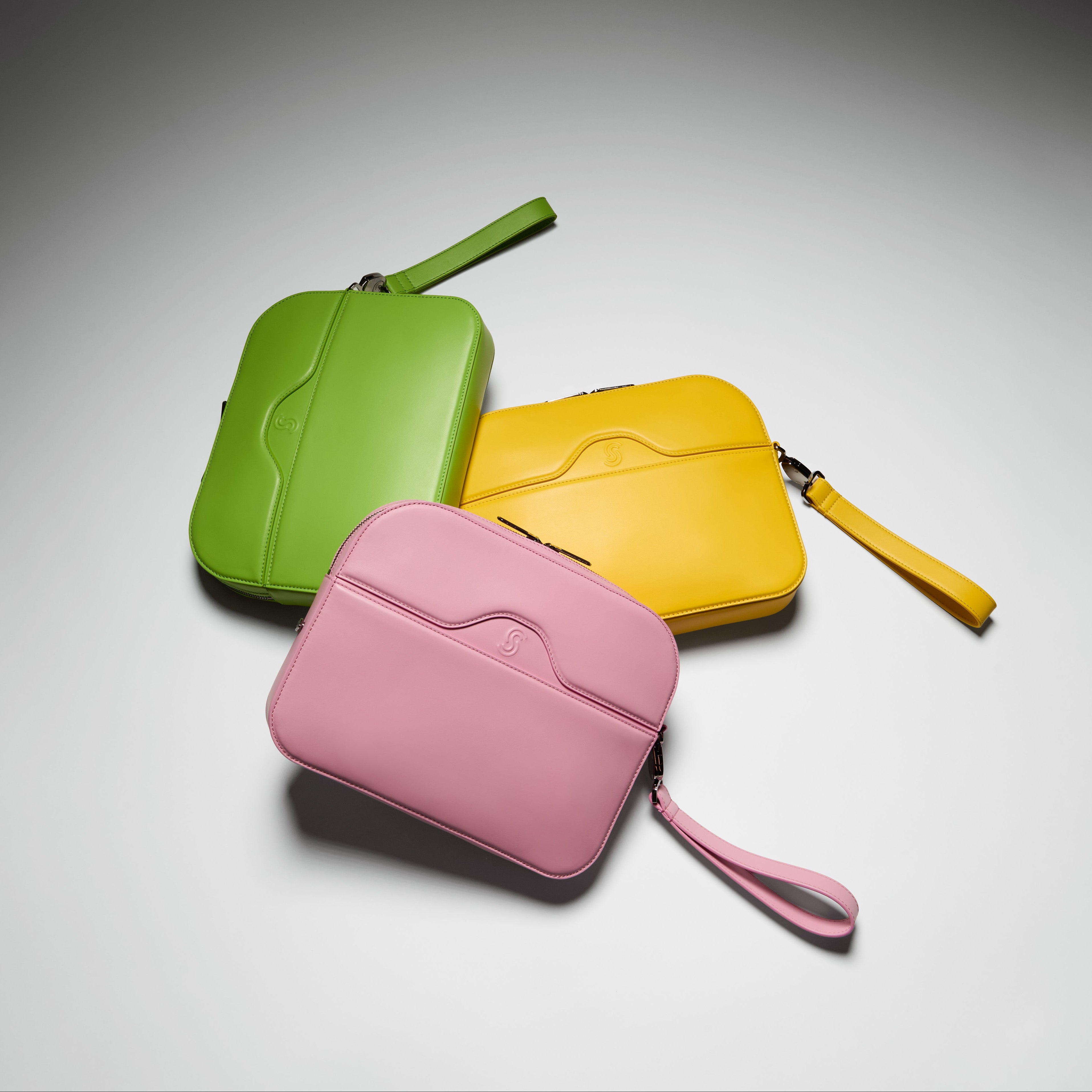 Three colorful pouches (green, pink, yellow) on a gray background